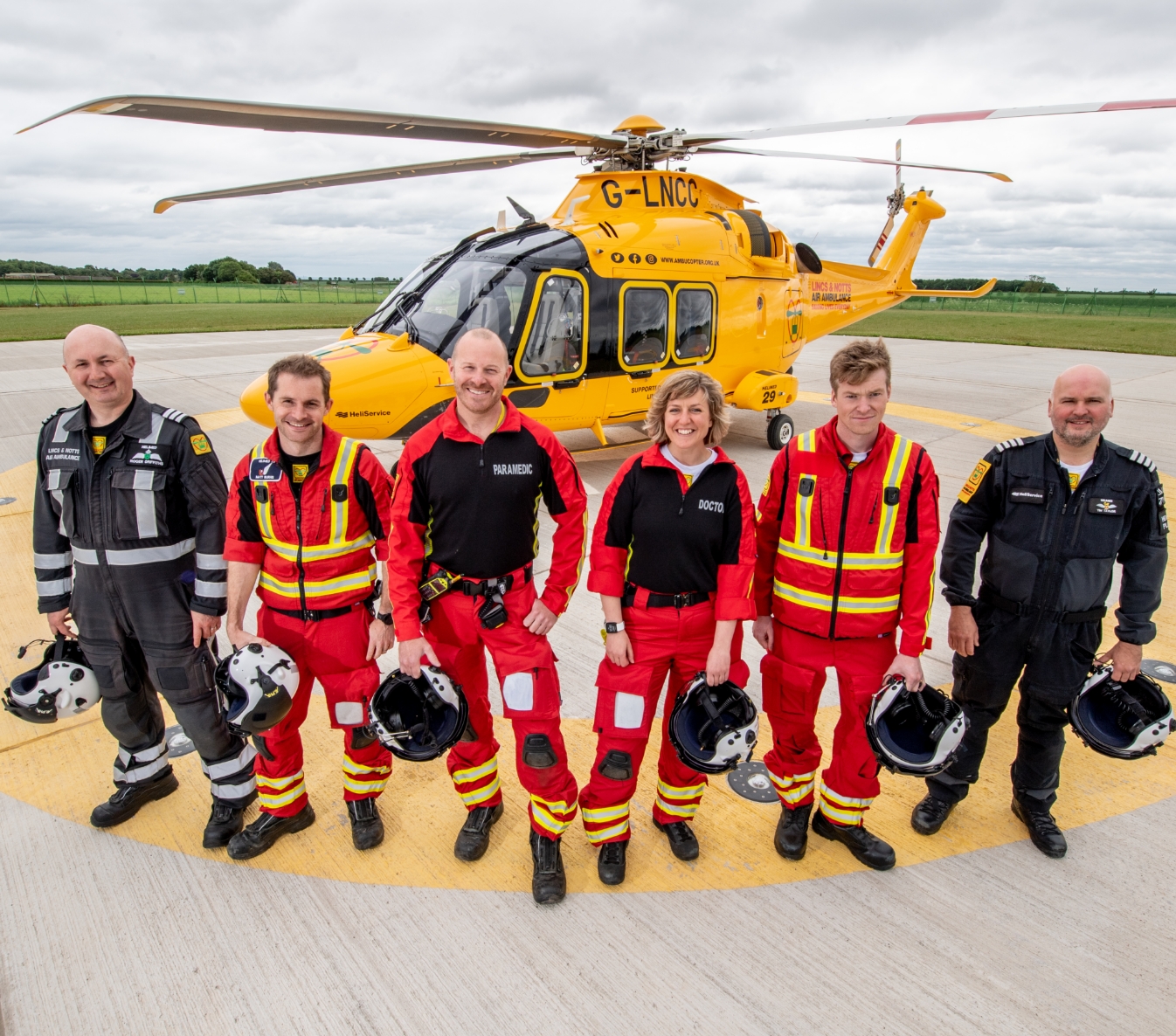 LNAA crew holding helmets in front of helicopter