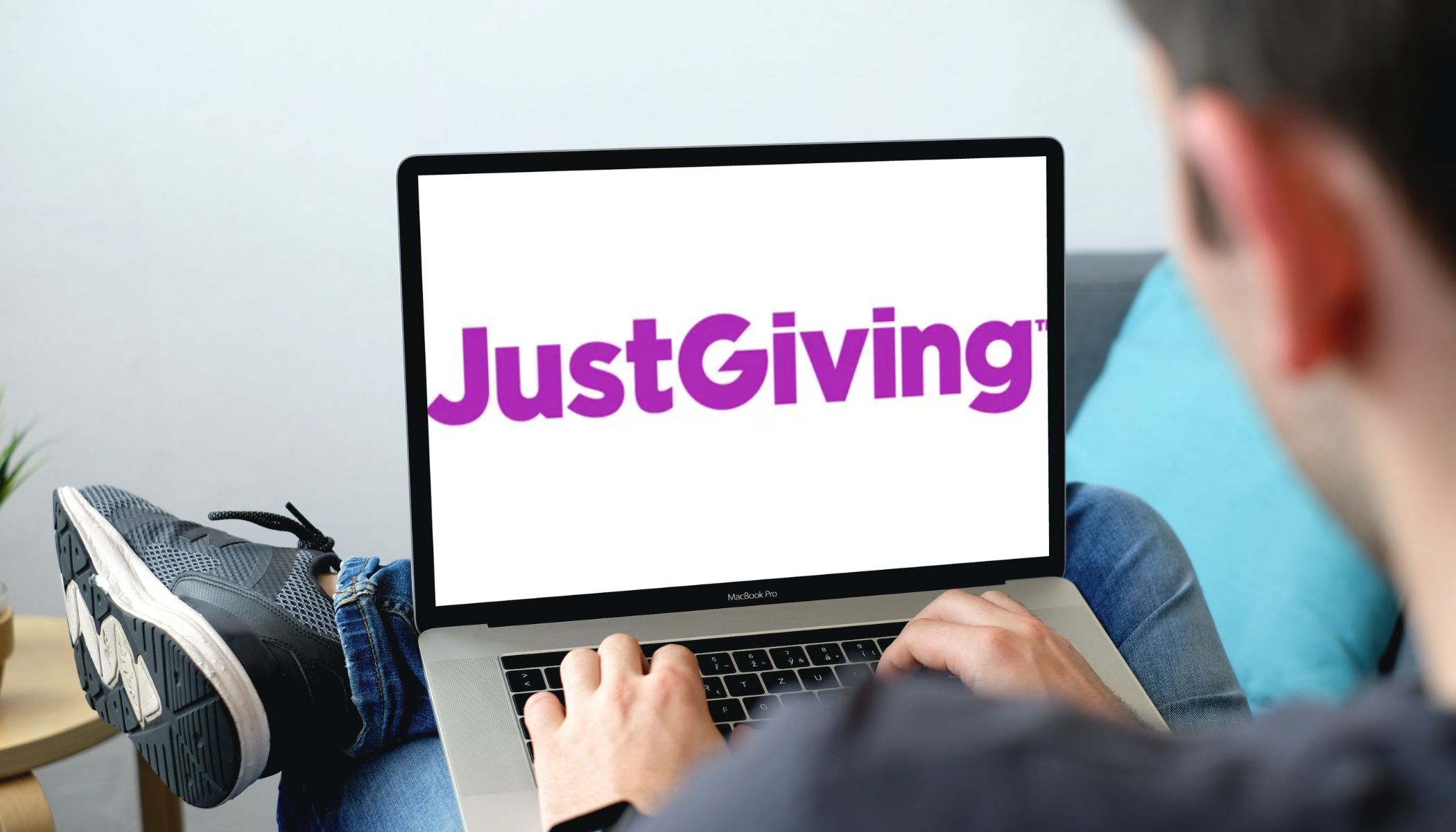 Man on his laptop with JustGiving logo