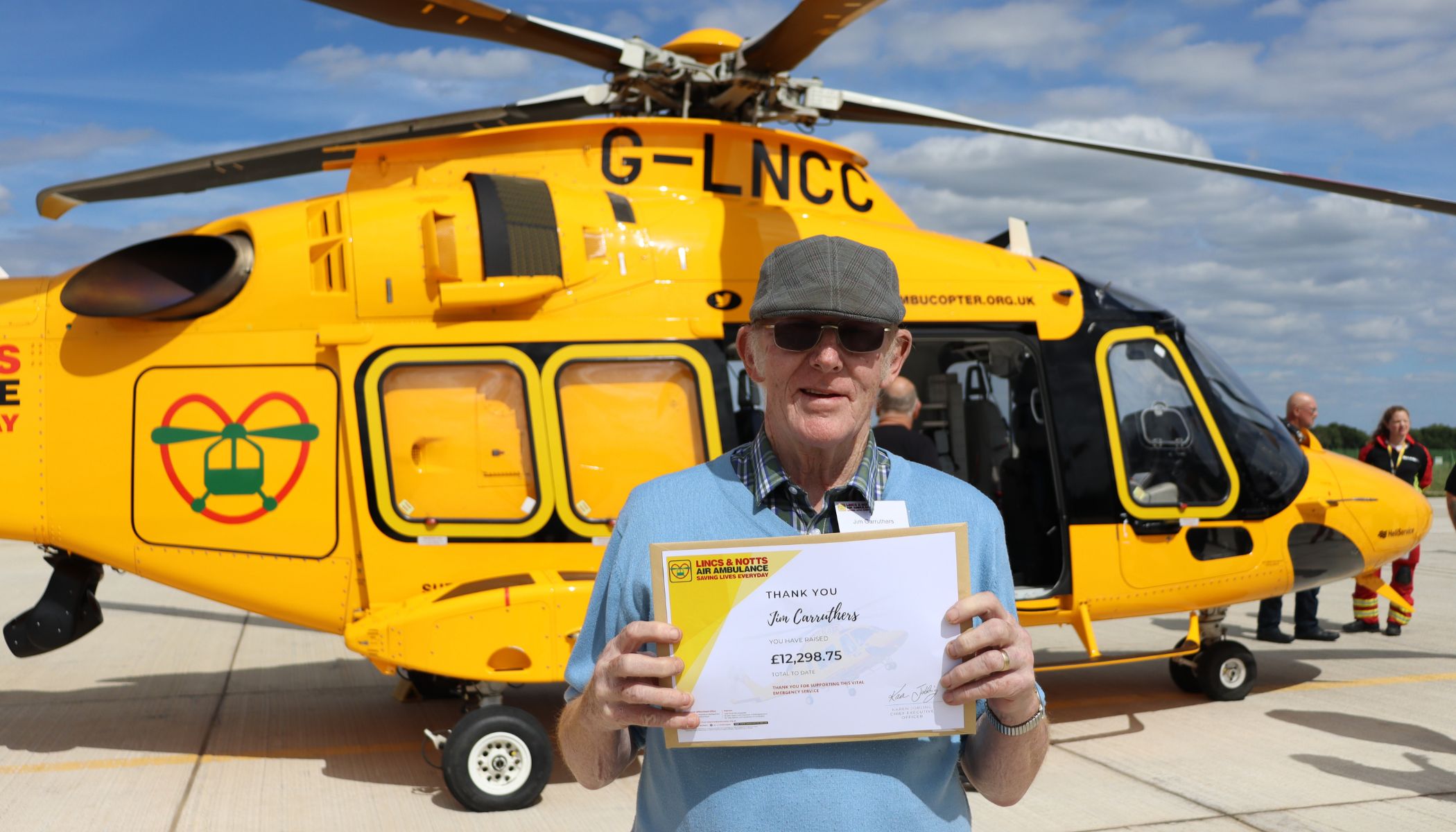 Supporter stood with a certificate in front of our helicopter