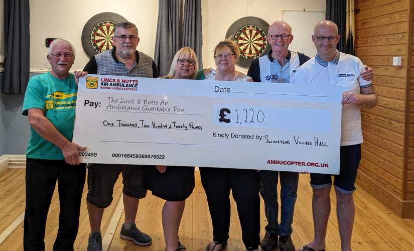 Swinstead village hall darts marathon present cheque to LNAA